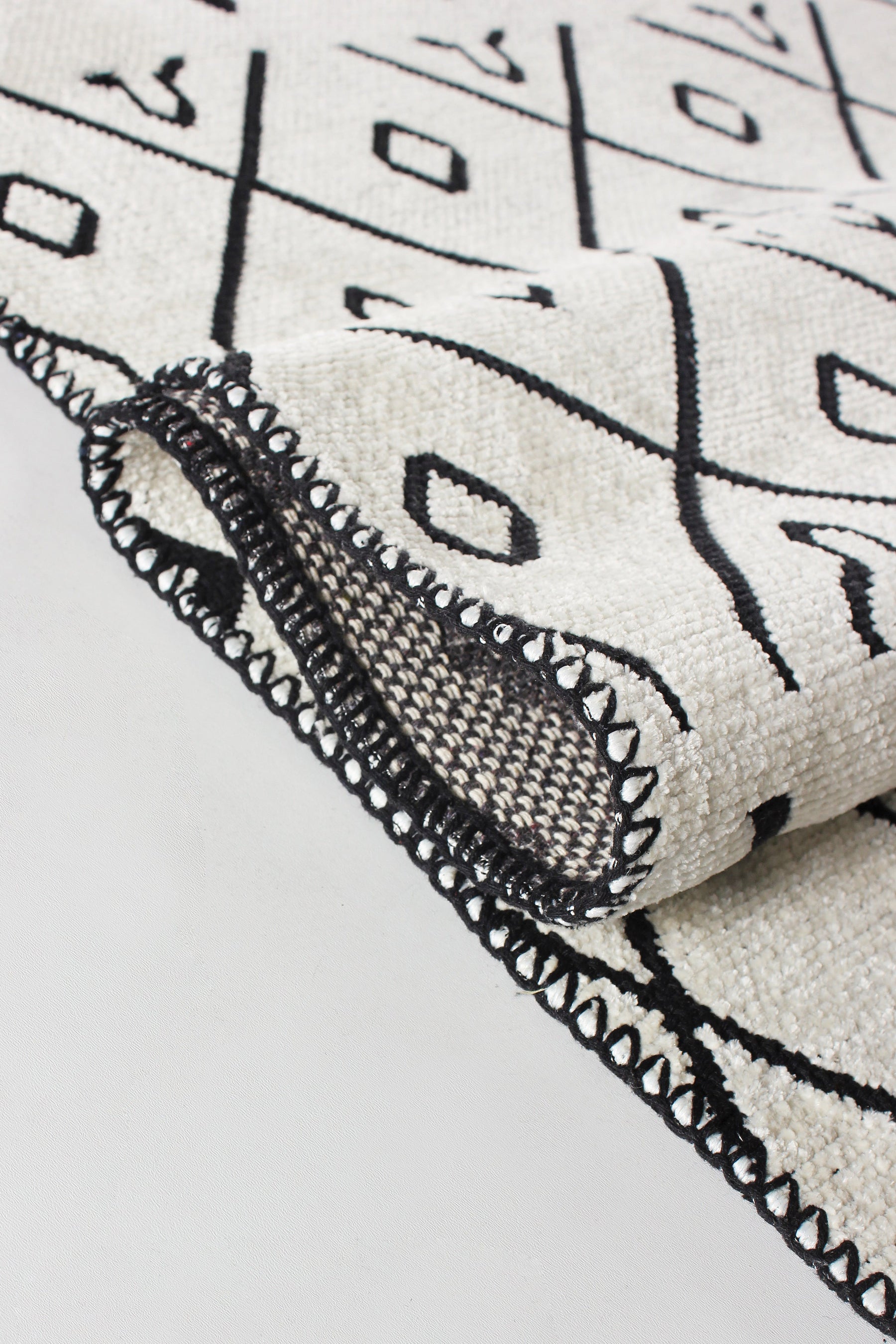 Washable tribal geometric rug by Netline Home featuring black and cream soft chenille with cotton backing on a floor.