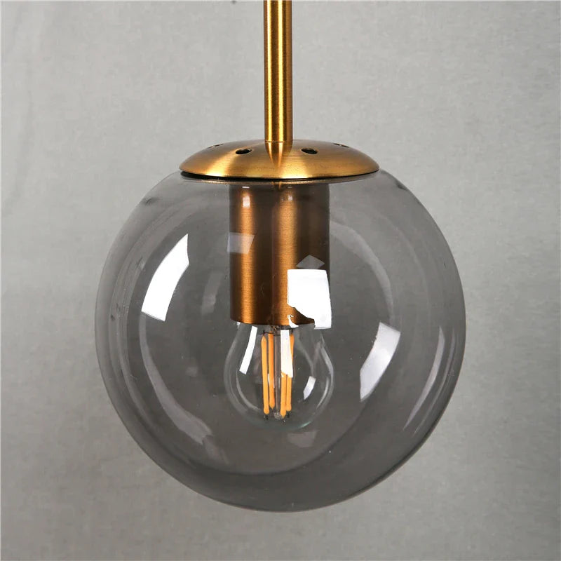Mid-century glass globe hanging wall light with amber, smoke, and clear glass by Light My House, showcasing its stylish design and warm glow.