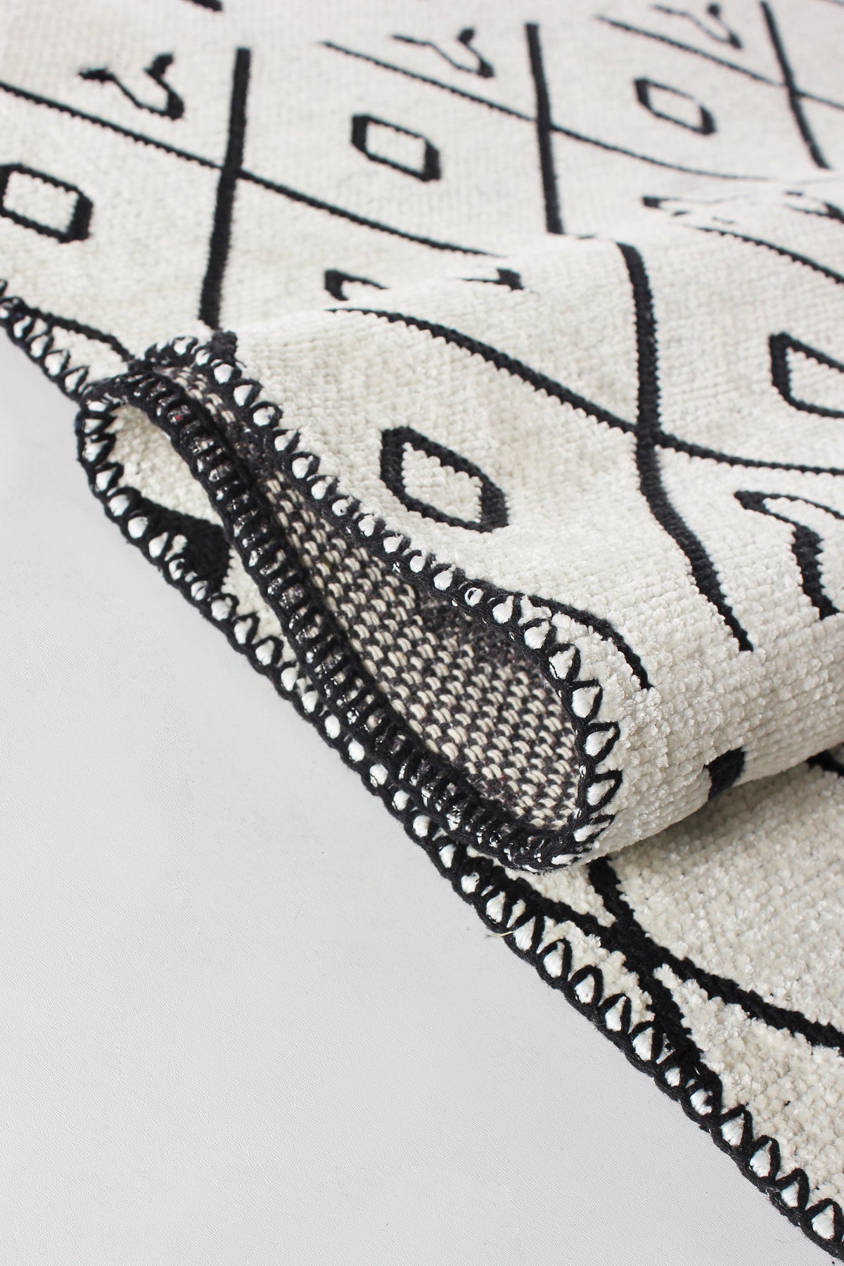 Washable tribal geometric rug by Netline Home featuring black and cream soft chenille with cotton backing on a floor.